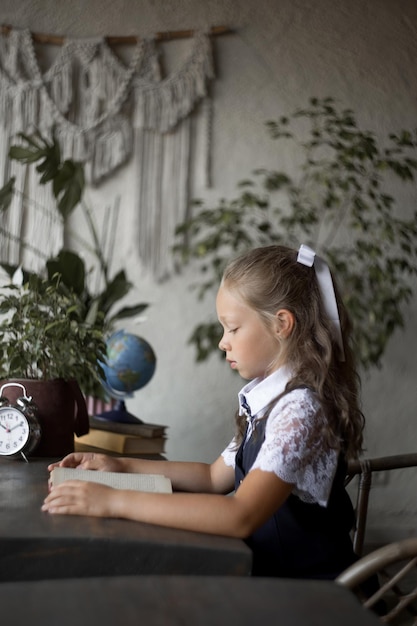 Studentessa primaria in uniforme scolastica con un libro