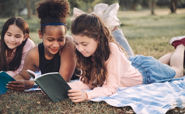 Studentessa sdraiarsi e leggere un libro con un amico nel parco