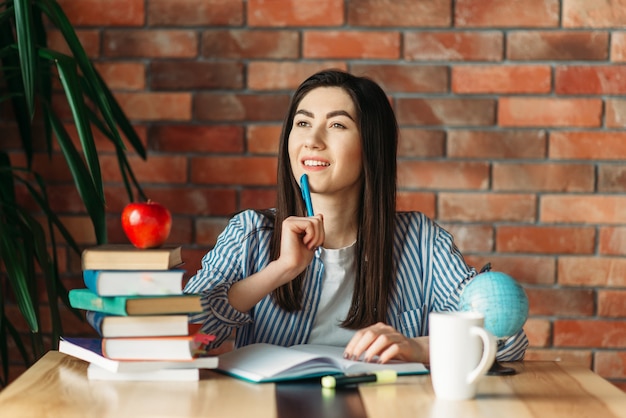 Studentessa seduta al tavolo con libri di testo