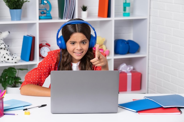 Studentessa seduta al tavolo utilizzando il laptop quando studia Felice ragazza faccia positiva