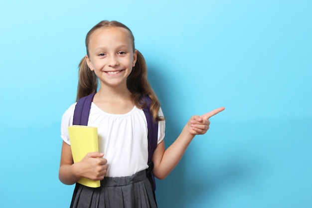 Studentessa sorridente carina con uno zaino scolastico su uno sfondo colorato