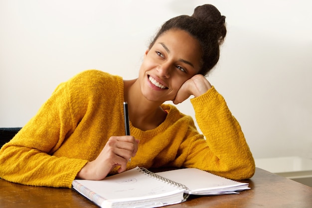 Studentessa sorridente che pensa con con la penna e la carta