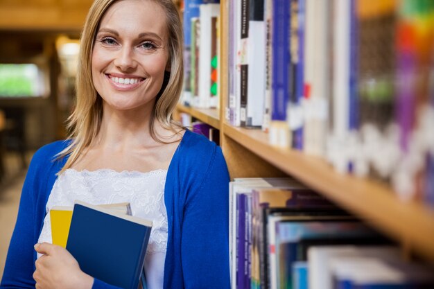 Studentessa sorridente che tiene un libro all&#39;università
