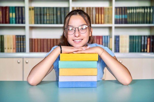 Studentessa sorridente guardando la telecamera con una pila di libri