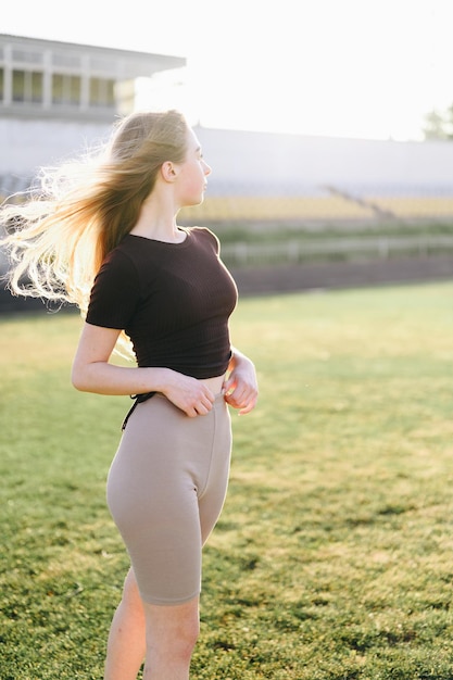 Studentessa sta allo stadio e guarda lontano La ragazza è pronta a fare sport