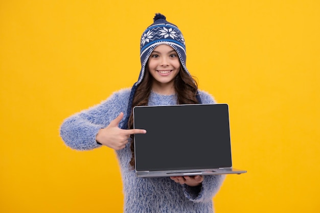 Studentessa studentessa in cappello di avvertenza tenere laptop sfondo giallo isolato Concetto di educazione alla conoscenza e all'apprendimento Felice faccia emozioni positive e sorridenti della ragazza adolescente