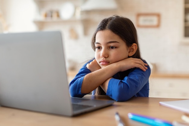 Studentessa triste che guarda il laptop che ha problemi a studiare online al coperto