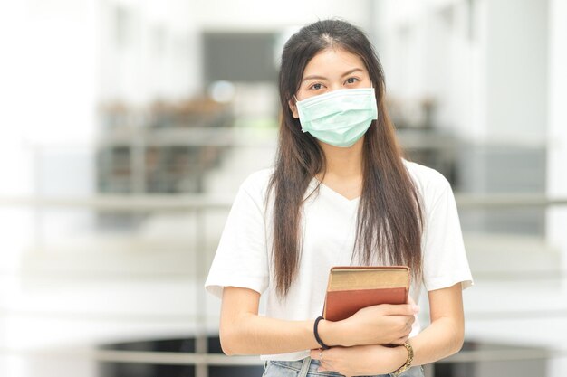 Studentessa universitaria asiatica in rilassato ritorno a scuola con maschera medica nel campus