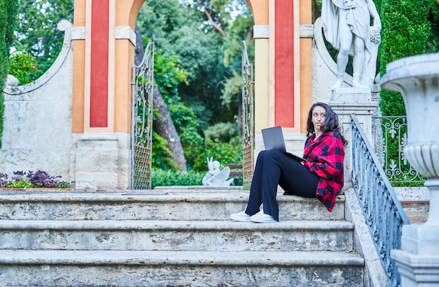 Studentessa universitaria che studia con il computer portatile nel parco