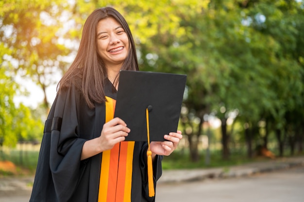 Studentesse con i capelli lunghi che indossano vestiti neri dell&#39;increspatura che esprimono gioia sulla graduazione all&#39;università.