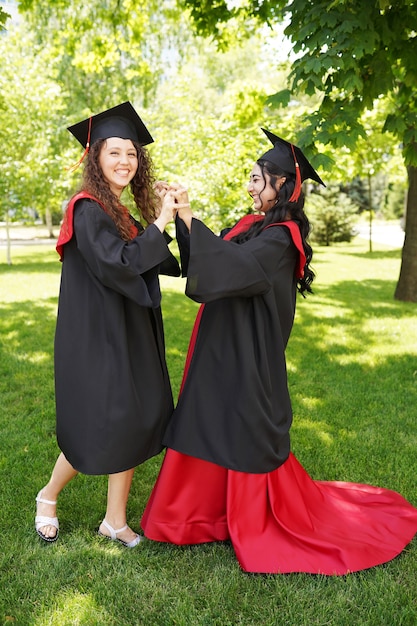 studentesse laureate di successo che indossano il berretto all'aperto vicino all'università