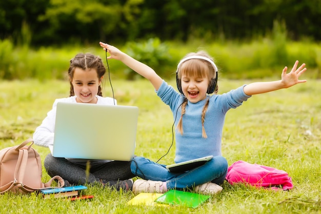 Studentesse piuttosto eleganti che studiano lezioni online nel cortile, distanza sociale durante la quarantena, autoisolamento, concetto di educazione online