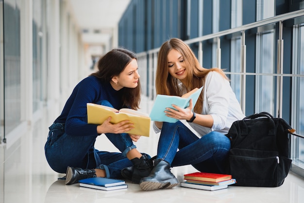 Studentesse sedute sul pavimento e leggere appunti prima dell'esame