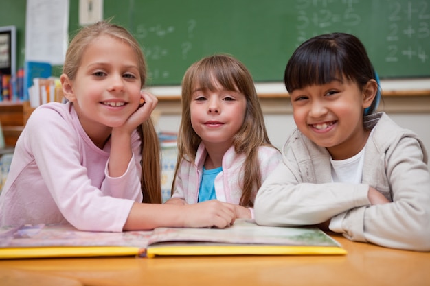 Studentesse sorridenti che leggono una fiaba al loro compagno di classe