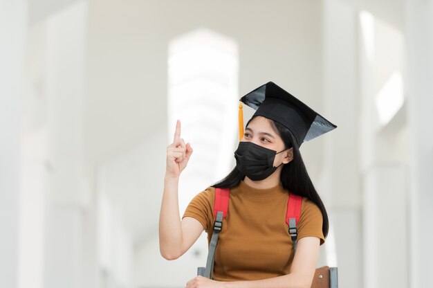 Studentesse universitarie, laureate, indossano cappelli neri, nappe gialle e indossano maschere durante l'epidemia.