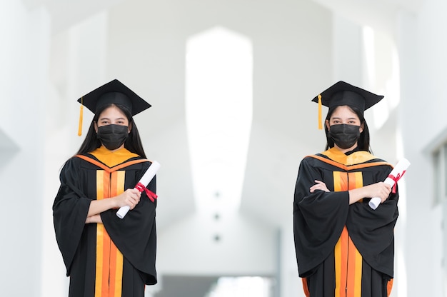 Studentesse universitarie, laureate, indossano cappelli neri, nappe gialle e indossano maschere durante l'epidemia.