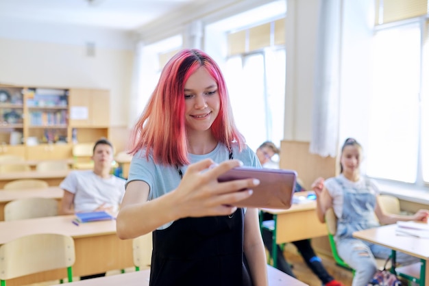 Studenti adolescenti che si divertono in classe brillante ragazza alla moda che scatta foto selfie con un gruppo di compagni di classe amici a scuola