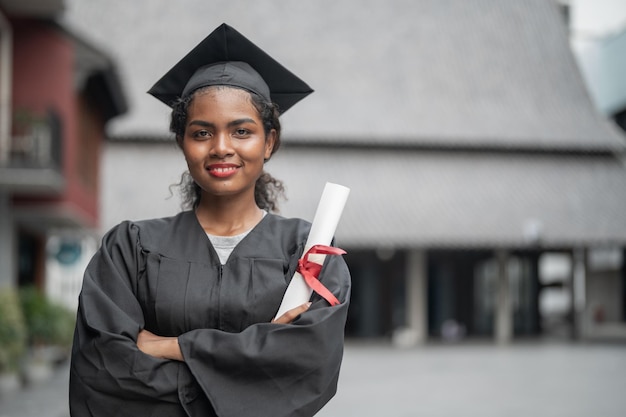 Studenti africani uomo e donna con abiti da laurea neri tengono il diploma e stanno insieme Con la sensazione di felice e aggraziato