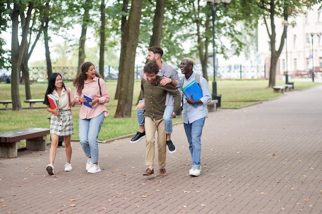 Studenti amici felici che camminano lungo il sentiero del parco