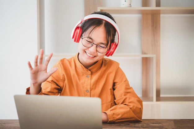 Studenti asiatici adolescenti in un abito giallo che indossano una cuffia comunicano tramite videoconferenza per l'apprendimento online. In videoconferenza tramite app. nuovo concetto normale