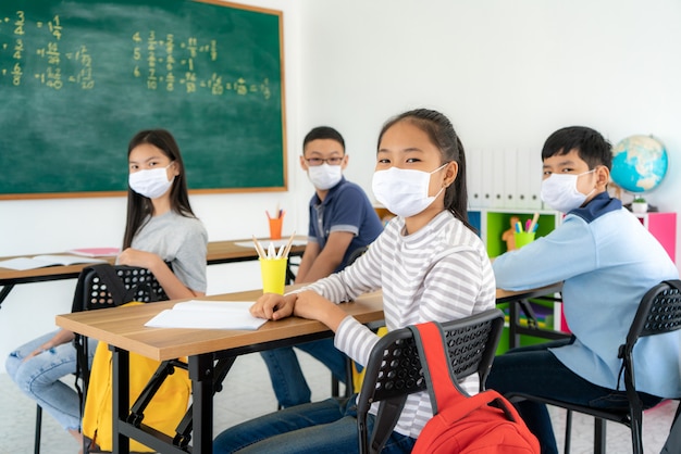 Studenti asiatici della scuola elementare che indossano maschera igienica