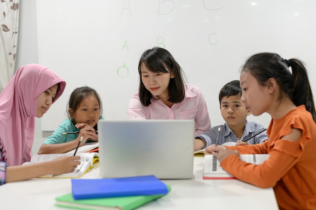 Studenti asiatici della scuola primaria. Insegnante di sesso femminile asiatico che insegna ai bambini.