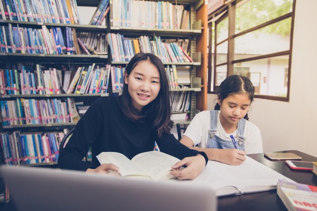 Studenti asiatici leggendo libri in biblioteca.