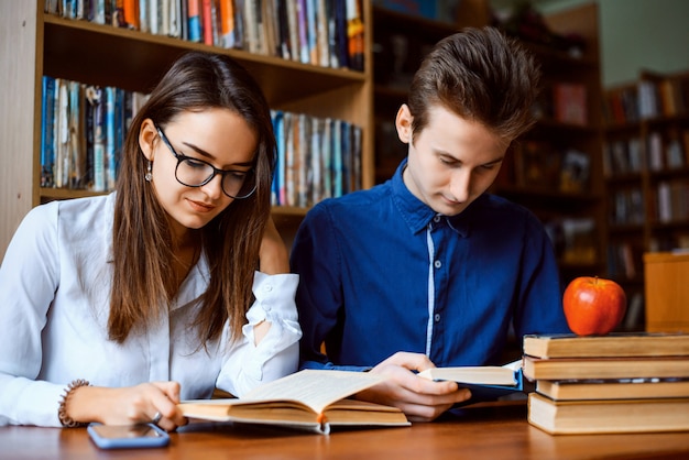 Studenti che collaborano con molti libri in biblioteca