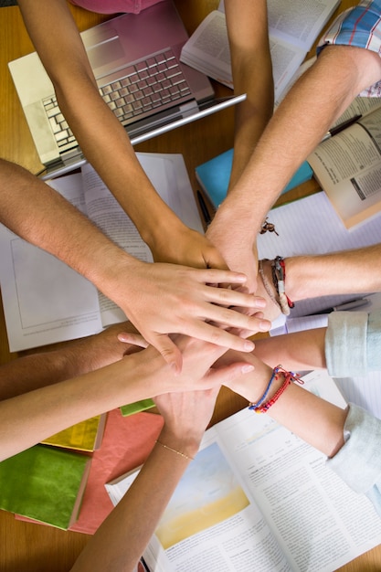 Studenti che dispongono le mani insieme sul tavolo della biblioteca