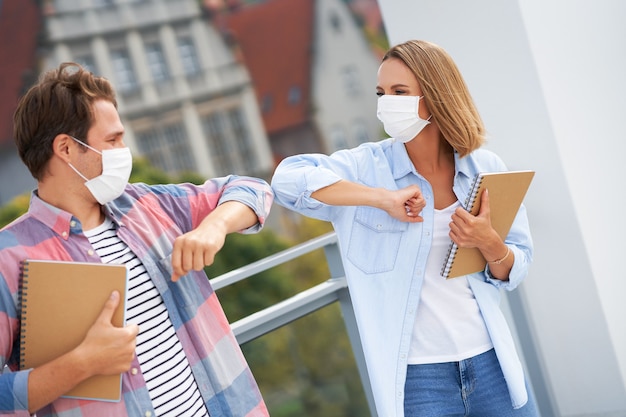 studenti che indossano maschere mentre salutano usando i gomiti nel campus