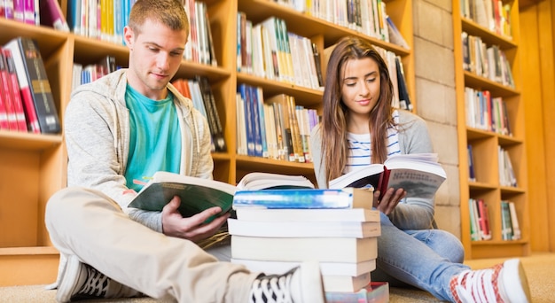 Studenti che leggono libri sul pavimento della biblioteca