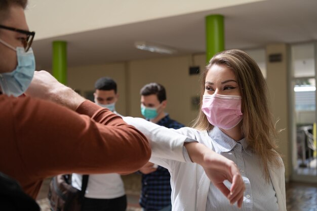 Studenti che salutano la nuova normalità del coronavirus stringere la mano e sbattere il gomito