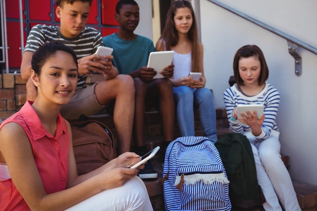 Studenti che utilizzano il telefono cellulare e la tavoletta digitale sulla scala