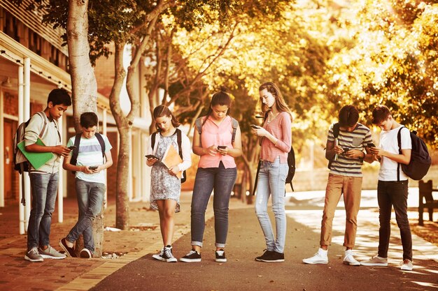 Studenti che utilizzano il telefono cellulare su strada nel campus