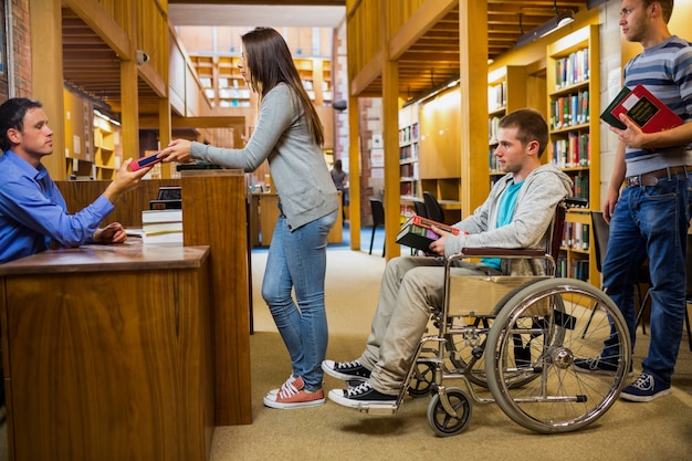 Studenti con handicappato in fila al banco della biblioteca