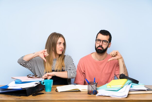 Studenti con molti libri che mostrano il pollice verso il basso