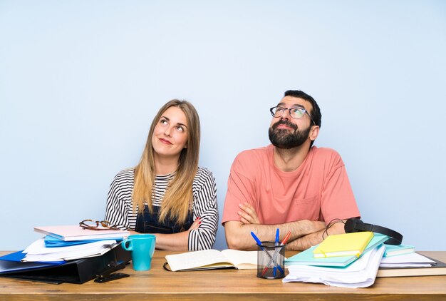 Studenti con molti libri che osservano in su mentre sorridono