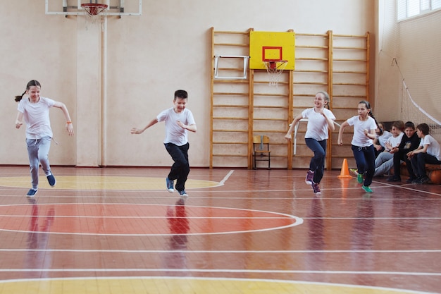 Studenti della scuola primaria una lezione di sport al chiuso. I bambini corrono e giocano a giochi mobili.