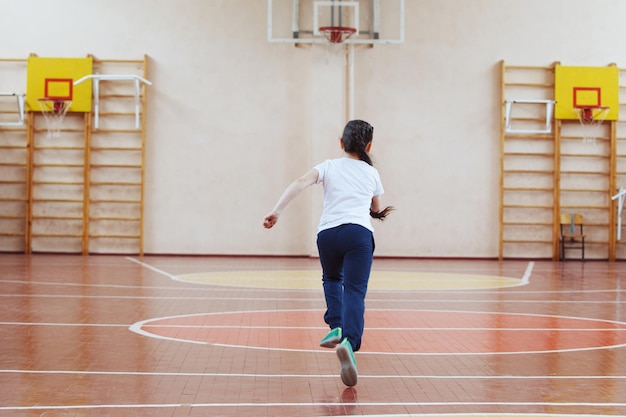 Studenti delle scuole primarie una lezione di sport al chiuso. I bambini corrono e giocano ai giochi mobili.