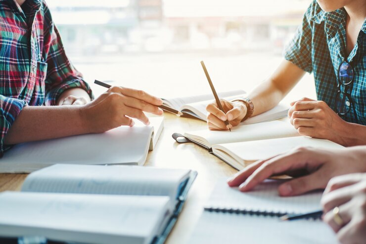Studenti delle scuole superiori o dei college che studiano e leggono insieme in biblioteca