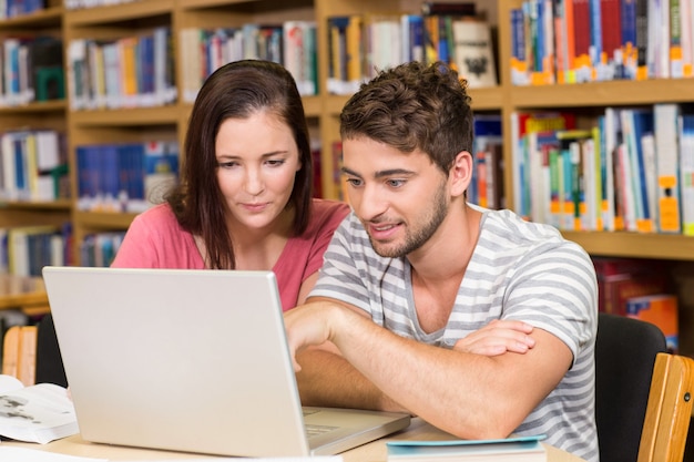 Studenti di college che utilizzano computer portatile nella libreria