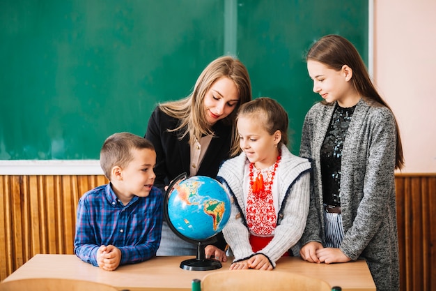 Studenti e insegnante di scuola guardando il globo