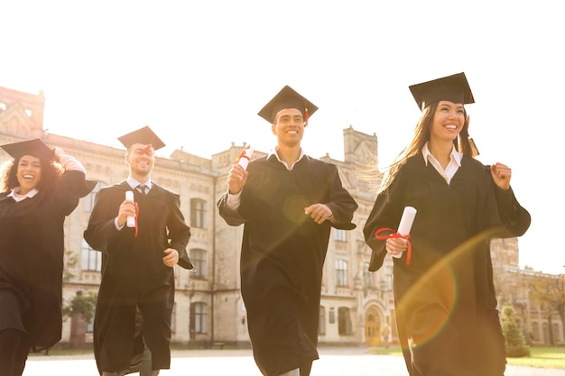 Studenti felici con diplomi all'aperto Cerimonia di laurea