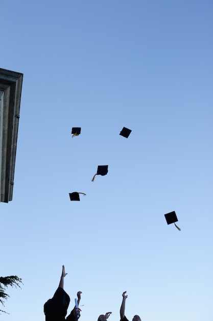 Studenti laureati che gettano il cappello in cielo