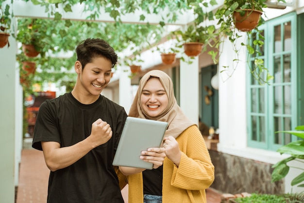 Studenti maschio e ragazza hijab felici quando si guarda allo schermo del tablet
