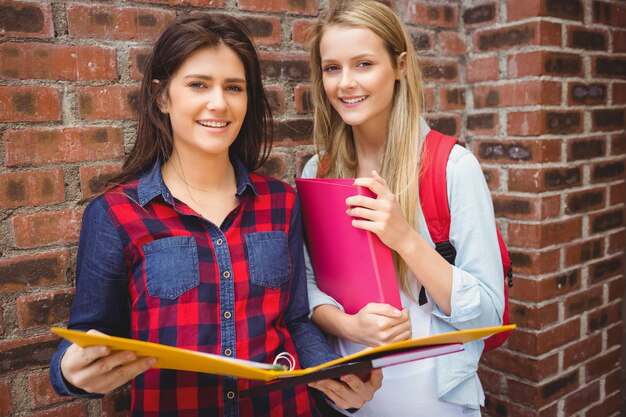 Studenti sorridenti con il raccoglitore che esamina macchina fotografica all&#39;università