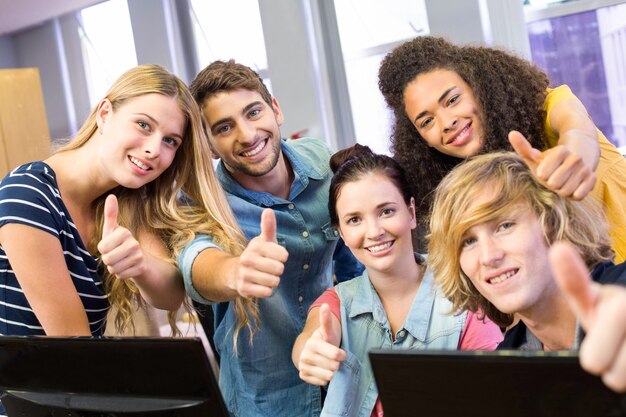 Studenti universitari che gesturing i pollici su