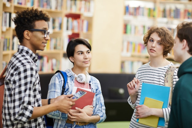 Studenti universitari multietnici che parlano nella biblioteca