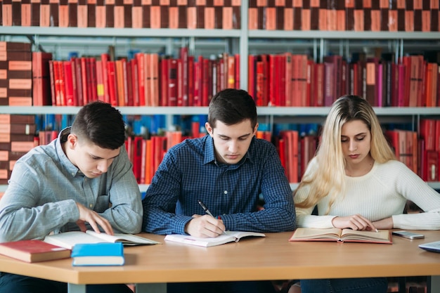 Studenti universitari seduti insieme a tavola con libri e laptop Giovani felici che fanno studio di gruppo in biblioteca