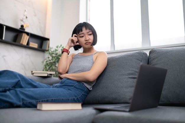 Studiando. Una ragazza seduta sul divano con un computer portatile e che sembra occupata